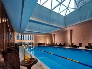a large swimming pool with chairs and a table at New Century Grand Hotel Hangzhou Shengtai in Hangzhou