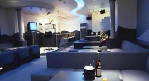 a room with blue couches and a stage with a bottle at Hotel Resea Minamichita in Minamichita