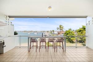 a kitchen with three chairs and a bar with a view of the water at Serenity Waters Riverfront Retreat - Walk to Mooloolaba in Mooloolaba