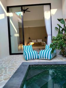 een paar blauw-wit gestreepte kussens naast een zwembad bij One bed room - 5 minutes to beach and cafe in Denpasar