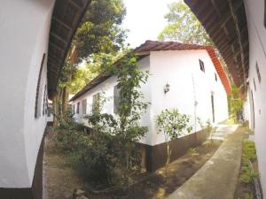 an archway leading to a white building with trees at Perhentian Tivoli Inn in Kampong Pasir Panjang