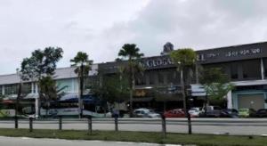 a building with palm trees in front of a street at M GLOBAL HOTEL in Kampong Jeram