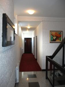 einen Flur mit einem roten Teppich und einem TV an der Wand in der Unterkunft Guesthouse Villa Milano in Kovin