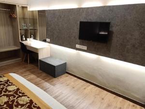 a hotel room with a desk and a tv on a wall at M GLOBAL HOTEL in Kampong Jeram