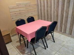 a pink table with four chairs in a room at Hotel Zamburger Sri Petaling in Kuala Lumpur