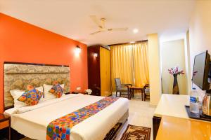 a bedroom with a large bed with an orange wall at FabHotel Bagatel in Calangute