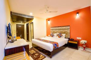 a bedroom with a large bed with an orange wall at FabHotel Bagatel in Calangute