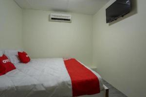 a bedroom with a bed with red pillows and a tv at OYO 822 Zande Motel Kuala Selangor in Kuala Selangor