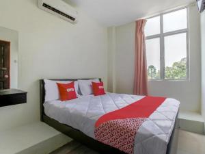 a bedroom with a bed with red pillows and a window at OYO 822 Zande Motel Kuala Selangor in Kuala Selangor