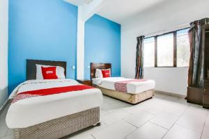 two beds in a room with blue walls at OYO 89571 Eco Palace hotel in Kuala Lumpur