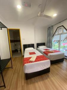 a room with two beds and a bathroom with a toilet at OYO HOME 90688 Kundasang Mount Garden in Kundasang