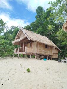 a wooden hut on the beach with trees in the background at Batanta Panorama Homestay in Dayang