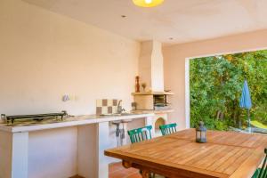 a kitchen with a wooden table and a large window at La Bignone in Régusse