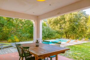 a patio with a wooden table and chairs and a pool at La Bignone in Régusse