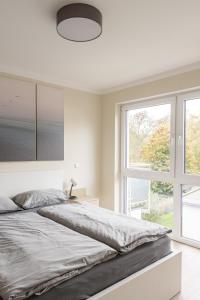 a white bedroom with a large bed and a window at Wohnen am Schloßpark in Lindlar