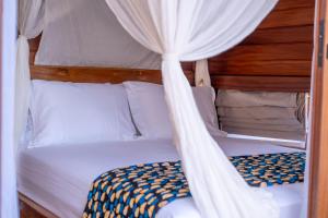 a bedroom with a canopy bed with white curtains at Naya Lodge in Mitsamiouli