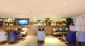 a restaurant with blue chairs and tables and a television at Echarm Hotel Guizhou Xingyi Jushan Avenue in Xingyin Wanfenglin Airport