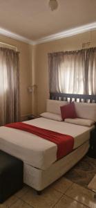 a bedroom with a large bed with white and red sheets at Boiketlo Lodge Gaborone in Gaborone +8 photos