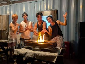 a group of people standing around a grill with fire at あさひシーサイドコテージ in Asahi +247 photos