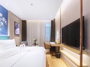 a hotel room with a bed and a large television at Jinjiang Inn Wuhan Linjiaohu Wanda Branch in Wuhan