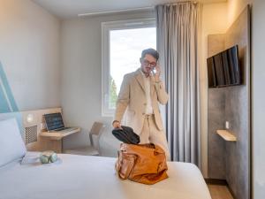 a man talking on a cell phone in a hotel room at Ibis Budget Orly Chevilly Tram 7 in Chevilly-Larue