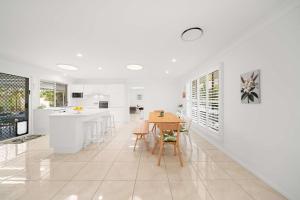 een keuken en eetkamer met witte muren en een tafel bij Santai Sands - Bribie Island 4BD Home in Woorim
