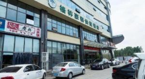 a building with cars parked in front of it at GreenTree Inn Linxi International Convention Center Express Hotel in Wangjiaqiao