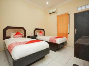 a bedroom with two beds with red and white sheets at OYO 2003 Female Guest House in Probolinggo