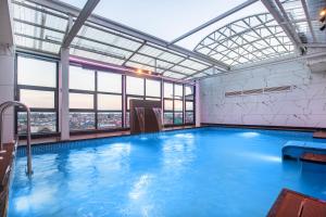 a large swimming pool with a large window at Hotel Shady Oaks by Stay Pattern in Srinagar