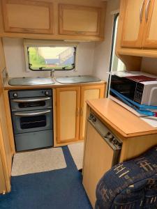 a small kitchen with a stove and a microwave at Beside the Seaside in Whangamata