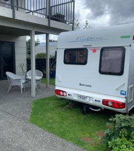 a white caravan parked in front of a house at Beside the Seaside in Whangamata
