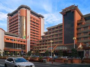 a car driving down a street in front of buildings at Quanzhou Hotel in Quanzhou