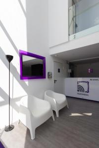 uma sala de estar com duas cadeiras brancas e uma televisão em YU! Smarthotels em Guayaquil