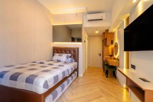 a bedroom with a bed and a desk and a sink at Tokyo Riverside Apartemen PIK 2- Kaito Inn Royale in Muara