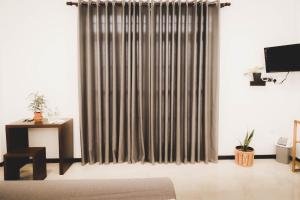 a living room with a curtain and a television at Cinnamon Forest Villa - Private Luxury Villa in Hikkaduwa in Hikkaduwa