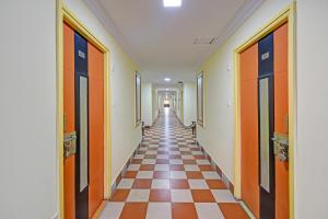a long hallway with a checkerboard floor and orange doors at FabHotel Ranjit Residency in Hyderabad
