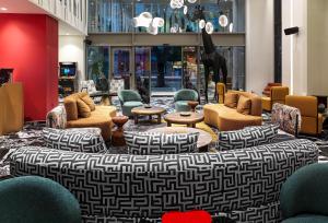 a lobby with chairs and couches and tables at NYX Hotel Thessaloniki in Thessaloniki