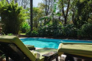 einen Pool mit zwei Liegestühlen im Hof in der Unterkunft Rivertrees Country Inn in Usa River