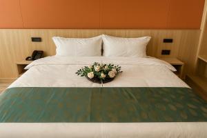 a white bed with a bouquet of flowers on it at Bishkek Crystal Luxury Smart Hotel Ala-Too Square Branch in Bishkek