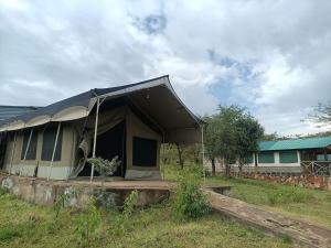 a tent in a field next to a house at Semadep Village Guest House in Sekenani