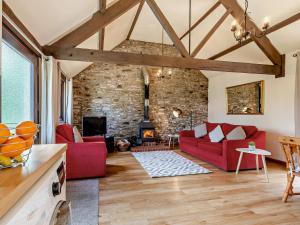 een woonkamer met rode meubels en een stenen muur bij 1 Bed in Bude WBARN in Sutcombe