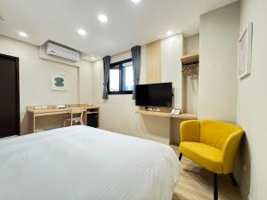 a bedroom with a white bed and a yellow chair at Yoshi Hotel - Tainan Sinmei Branch in Tainan