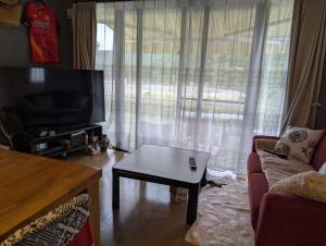 a living room with a couch and a tv and a table at Nago city 民泊U in Nago