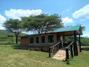 a small house with a green roof in a field at Semadep Village Guest House in Sekenani