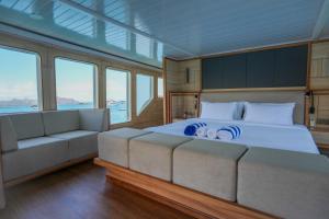 a bedroom with a bed and a couch and windows at Komodo Top Sailing in Labuan Bajo