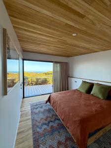 a bedroom with a large bed with a wooden ceiling at Sommerhus Danish inspired beach front retreat in Vivonne Bay