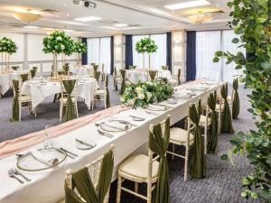 a long banquet hall with white tables and chairs at Mercure Nottingham Sherwood in Nottingham