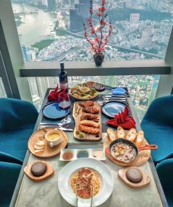 a table with plates of food and wine in front of a window at The Grand Residence at Vinhomes in Ho Chi Minh City