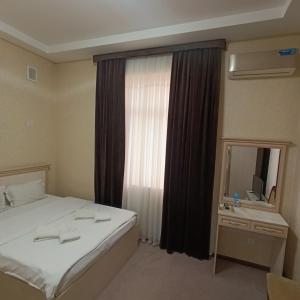 a hotel room with a bed and a window at Grand Caravan Hotel in Yakkasaray
