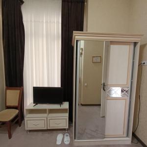 a room with a television on a dresser with a mirror at Grand Caravan Hotel in Yakkasaray